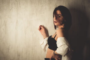 Beautiful young sedative woman in lingerie leaning on the wall at home.